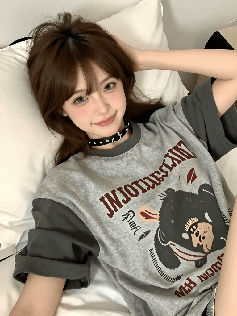 A cute 21-year-old woman with brown hair in a half-up style with bangs, striking green/hazel eyes, wearing a choker necklace and a trendy oversized t-shirt, lounging playfully on a bed with pillows, giving a cheeky smile in a softly lit cozy bedroom.